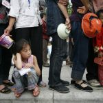 Eradicate Poverty, child waits in a queue for food