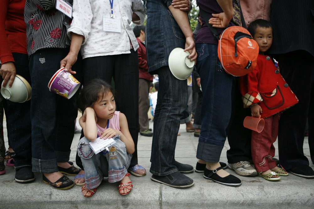 Eradicate Poverty, child waits in a queue for food